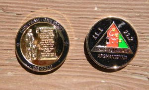 Two commemorative coins placed side by side on a wooden surface. The left coin features an engraved monument and soldier; the right coin displays an emblem with "111 ESB Afghanistan" text.